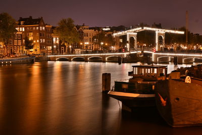 Illuminated bridge over river in city at night