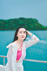 Portrait of young woman standing against sky