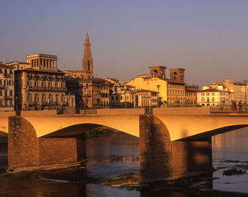 Arch bridge over river against buildings in city