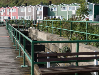 Empty bench by railing against buildings