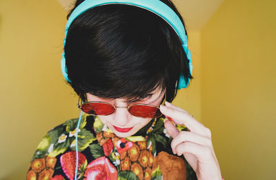 Close-up of woman wearing headphones against colored background