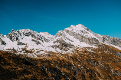 Scenic view of snowcapped mountains against clear blue sky
