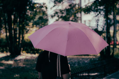 Rear view of woman with umbrella standing on rainy day