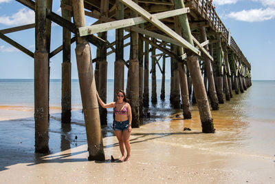 Woman standing against pier at beach