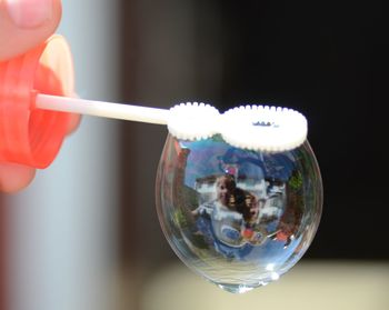 Reflection of boy on bubble during sunny day