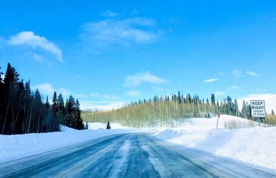 Road amidst trees against sky during winter