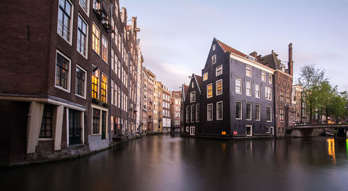 Canal amidst buildings against sky