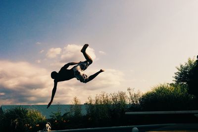 Full length of young woman jumping against sky