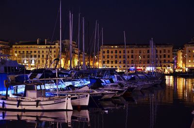 Sailboats moored at harbor against sky at night