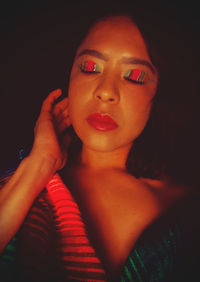 Close-up portrait of young woman against black background