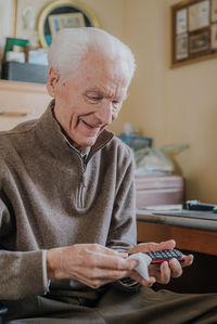 Senior man cleaning mobile phone at home