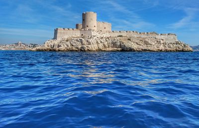 Castle by sea against blue sky