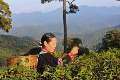 Woman with arms raised on mountains against plants