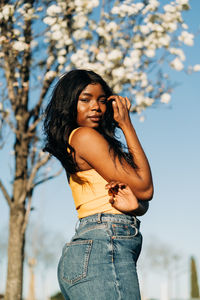 Young woman standing against tree