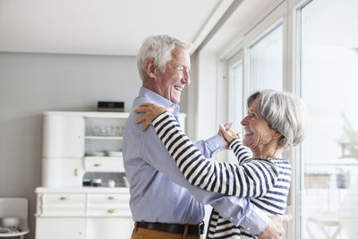Senior couple dancing together at home at home