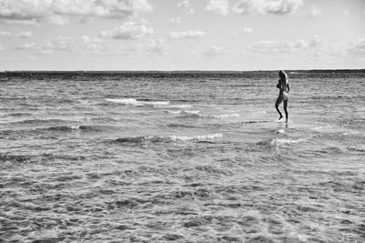 Rear view of woman walking on shore at beach