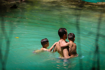 Father swimming with sons in lake