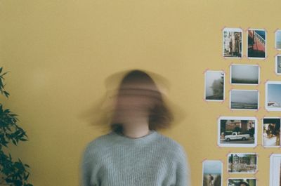 Woman shaking head while standing against wall