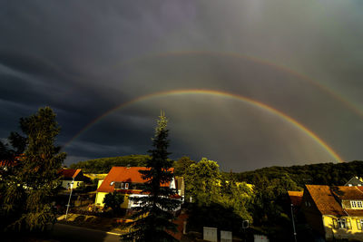 Rainbow over buildings in city against sky