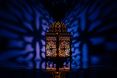 Black lantern with reflection from blue background for the holy month of ramadan kareem.