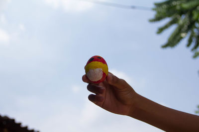 Low angle view of person holding ice cream against sky