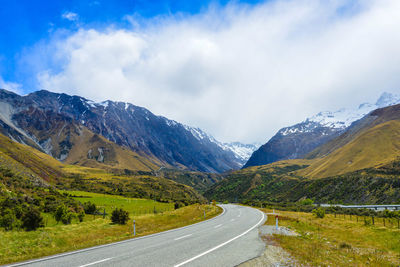 Road leading towards mountains against sky