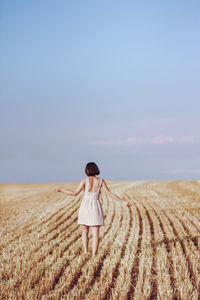 Woman standing on field against sky