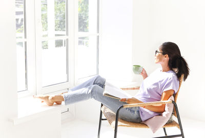 Side view of woman sitting on chair