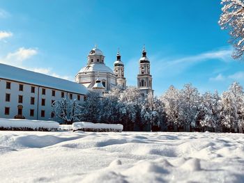 Snow covered trees by buildings against sky