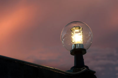 Low angle view of illuminated street light against orange sky