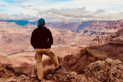 Rear view of man looking at mountains against sky