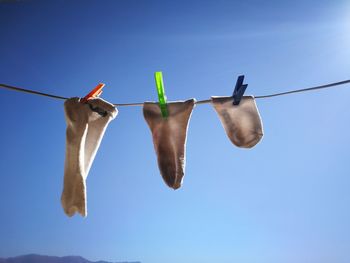 Low angle view of clothespins on clothesline against blue sky