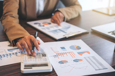 Midsection of man working with book on table