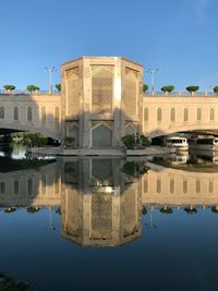 Reflection of building in water against clear blue sky