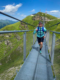 Full length of man on footbridge against sky