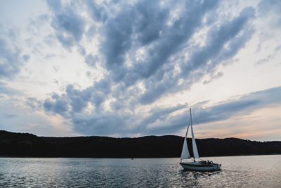 Sailboats sailing in sea against sky during sunset