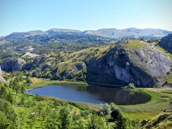 Scenic view of lake and mountains against clear blue sky