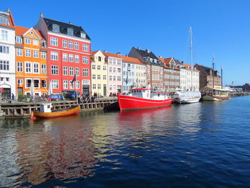 Boats moored at harbor against clear blue sky