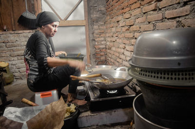 Grandma preparing peanut peyek at traditional kitchen