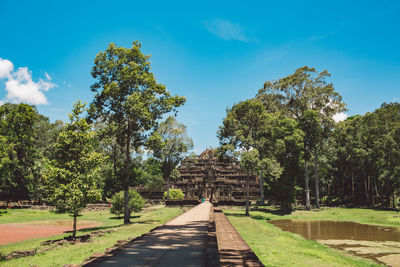 Footpath towards a temple amidst trees against sky