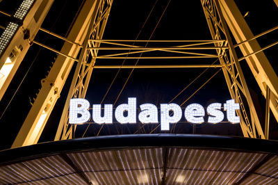 Low angle view of illuminated text against sky at night