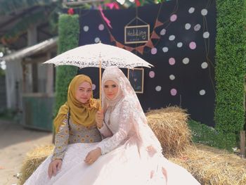 Portrait of two woman in traditional dress sitting under umbrella 