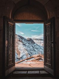 Snowcapped mountains against sky seen through window