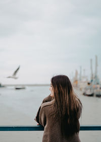 Side view of woman looking at sea against sky