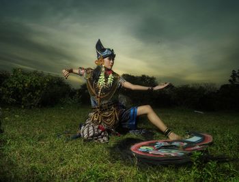 Rear view of woman ' jatilan 'dancer sitting on field