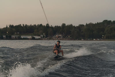 Latino mas doing wakeboarding in a lake with mountains in the background