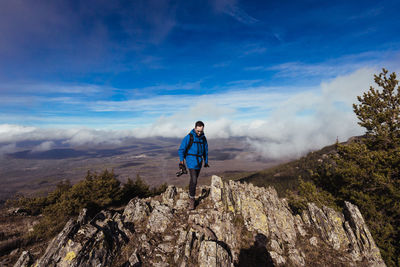 Full length of man standing on rock against sky
