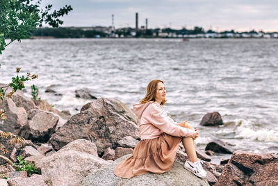 Woman sitting on rock by sea