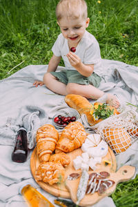Side view of boy eating food on field