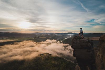 Rear view of man standing on rock against sky